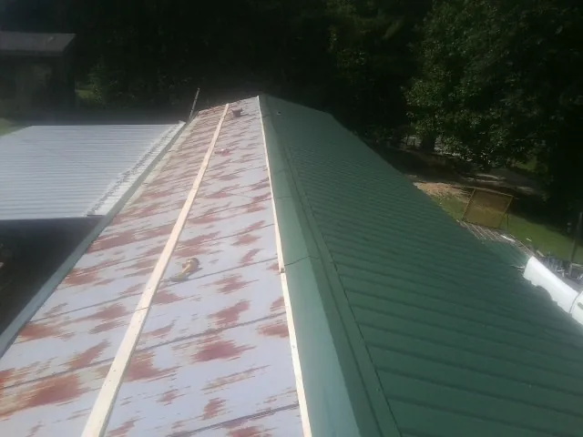 Old rusted panels beside newly installed green metal roofing — Wind Damage Roof Repair by Roofing Brothers in Gary
