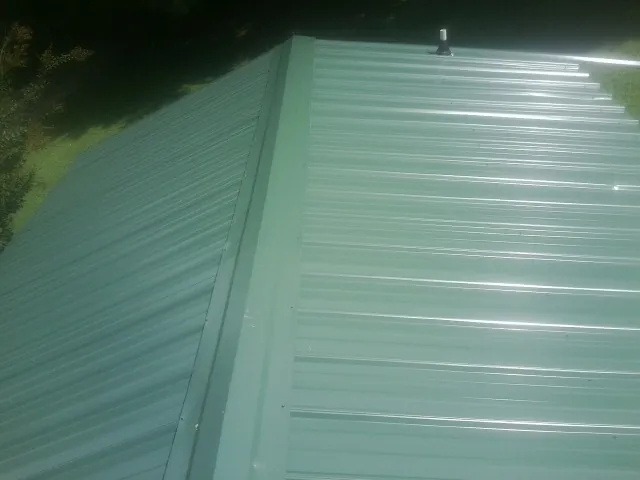 New green metal panels meeting at the ridge of a roof — Flat Roof Repair work by our crew in Gary