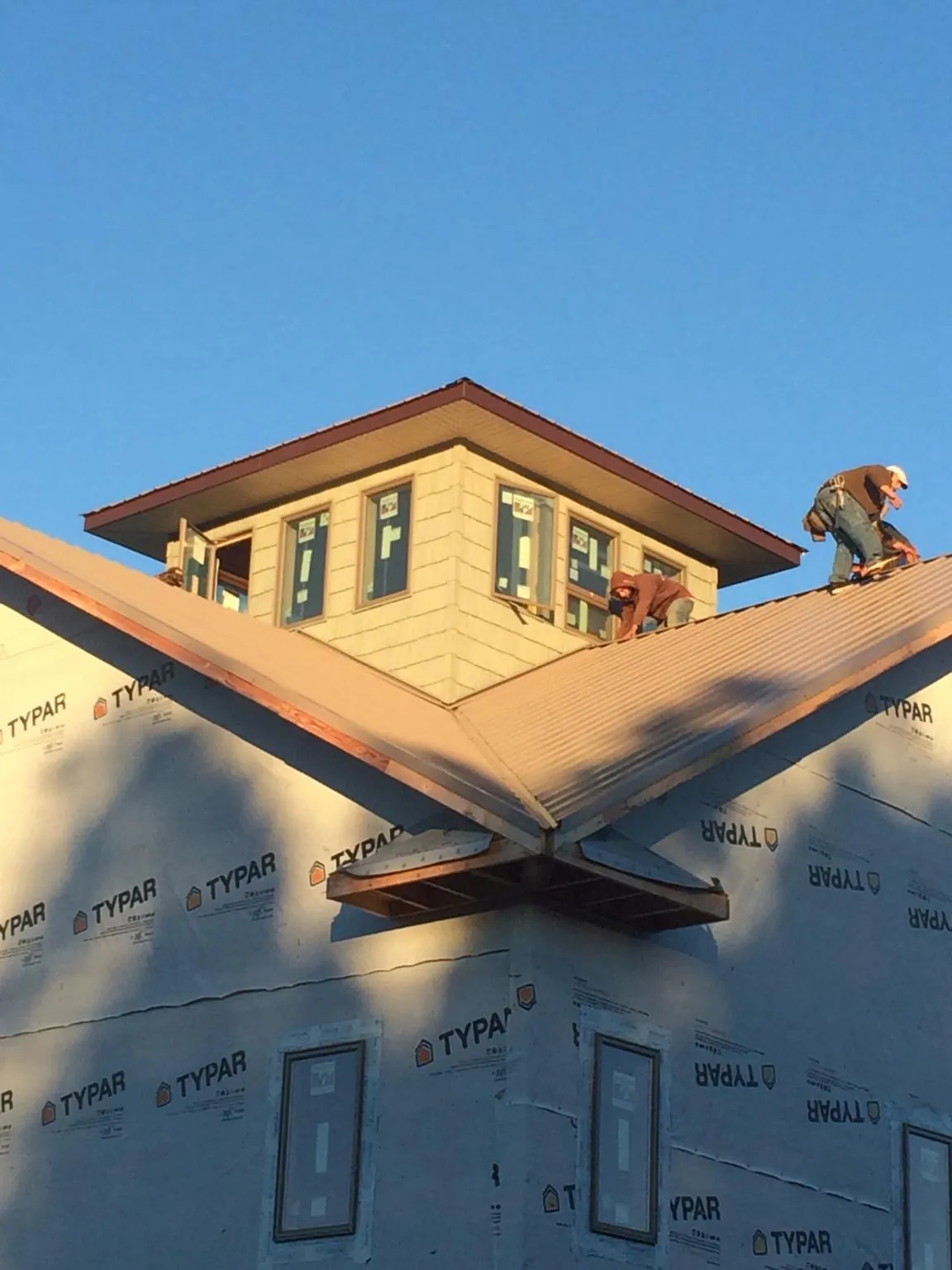 Roofers working around a rooftop cupola on a new metal roof at sunset — Roof Waterproofing in Gary by Roofing Brothers